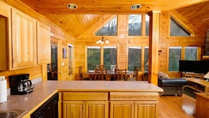 A wooden cabin interior with a kitchen, dining area, and a cozy seating area. - Secluded 3BR Cabin w Hot Tub Dog Friendly Sleeps12 (Pigeon Forge)