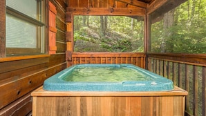 A wooden cabin with a hot tub and a large window overlooking a forest. - Secluded 3BR Cabin w Hot Tub Dog Friendly Sleeps12 (Pigeon Forge)
