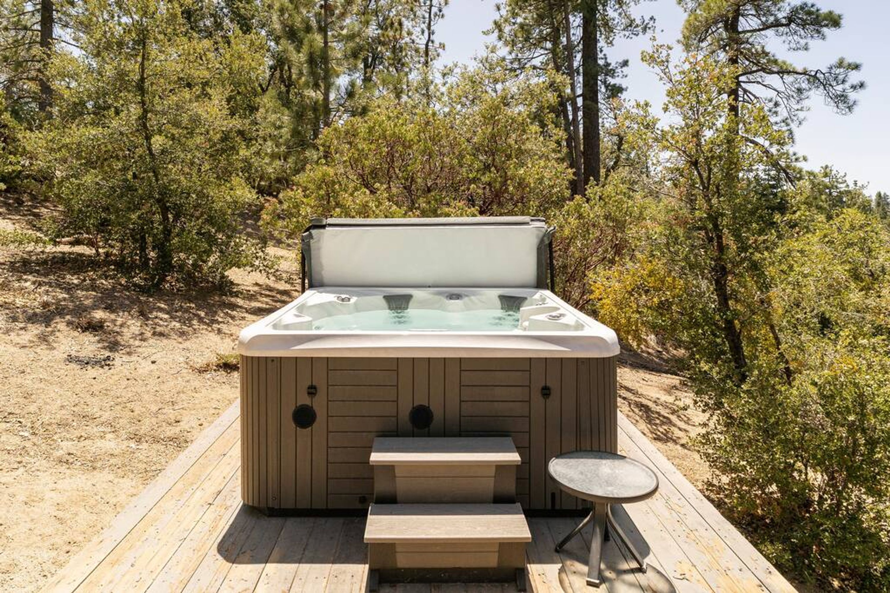 A hot tub on a wooden deck surrounded by trees.