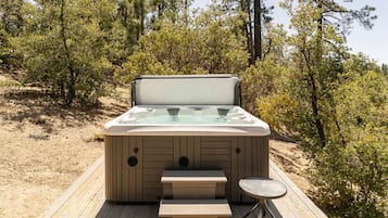 A hot tub on a wooden deck surrounded by trees.