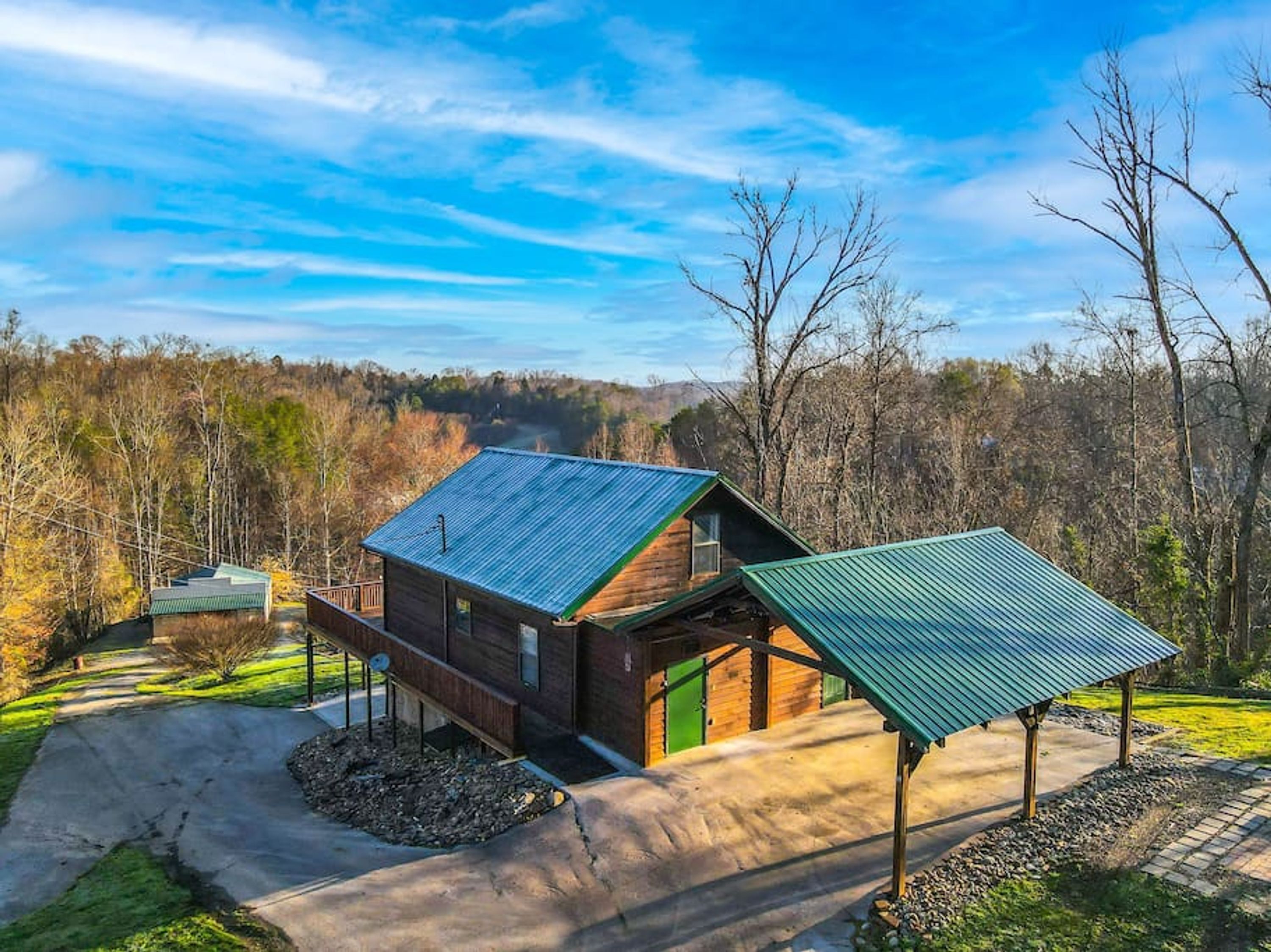 Eine moderne Holzhütte mit geneigtem Dach, einer Veranda und Blick auf ein bewaldetes Gebiet.