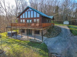 A two-story log cabin with a balcony, stone foundation, and a covered outdoor area. - Dog Friendly Views Hot Tub Close to PF Gsmnp (Sevierville)