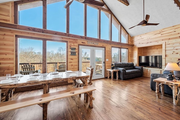 A spacious living area with a large wooden dining table, comfortable seating, a flat-screen TV, and a ceiling fan. - Dog Friendly Views Hot Tub Close to PF Gsmnp (Sevierville)
