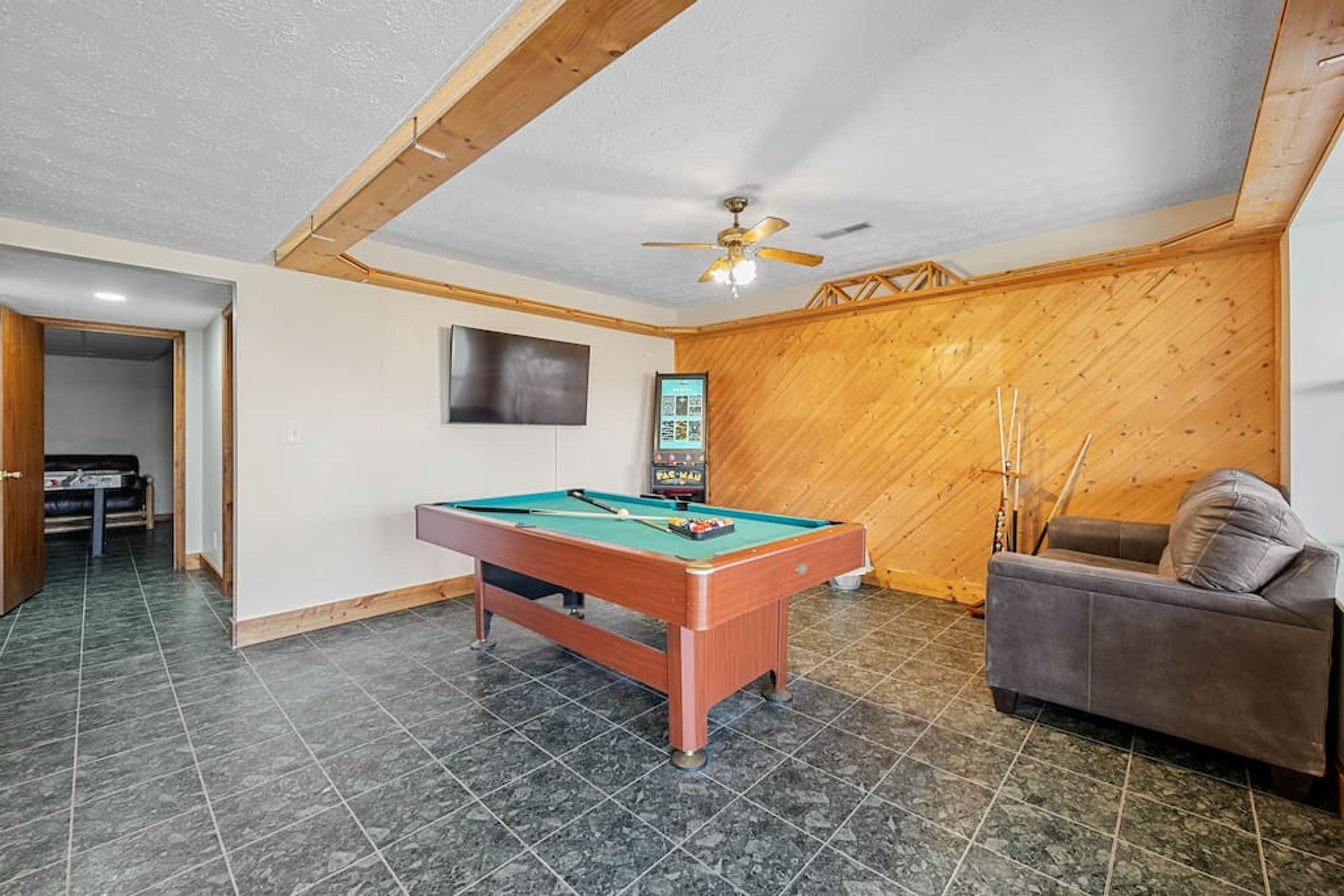 A room with a pool table, a sofa, and a ceiling fan.