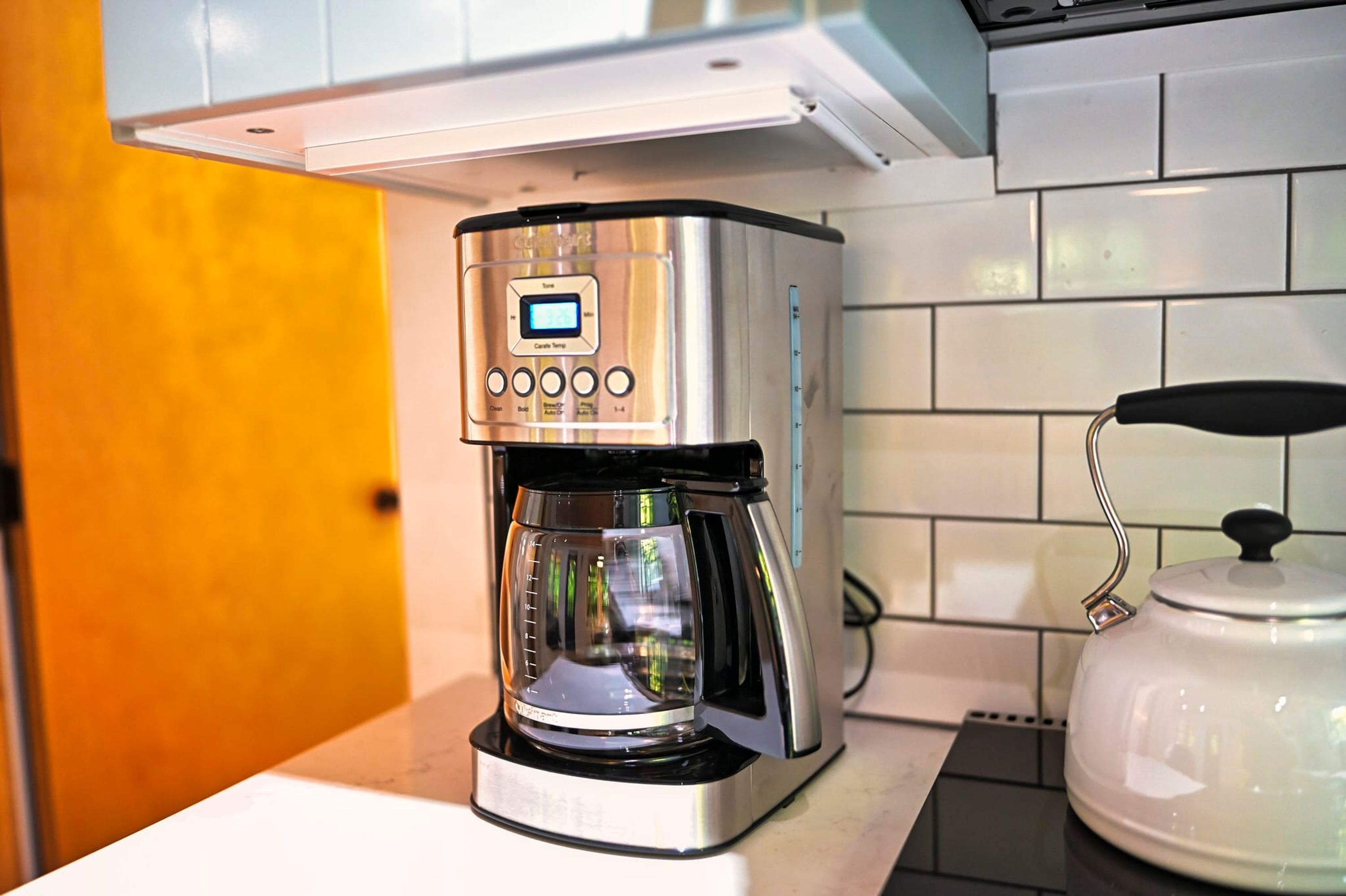 A modern coffee maker with a digital display and control buttons on a kitchen counter.