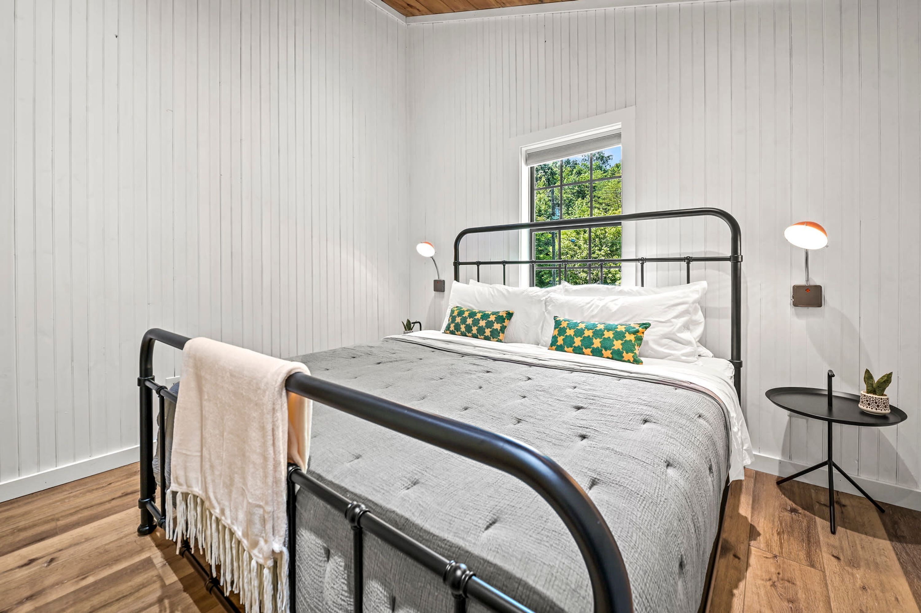 Un dormitorio ordenado con cama, mesitas de noche y ventana.