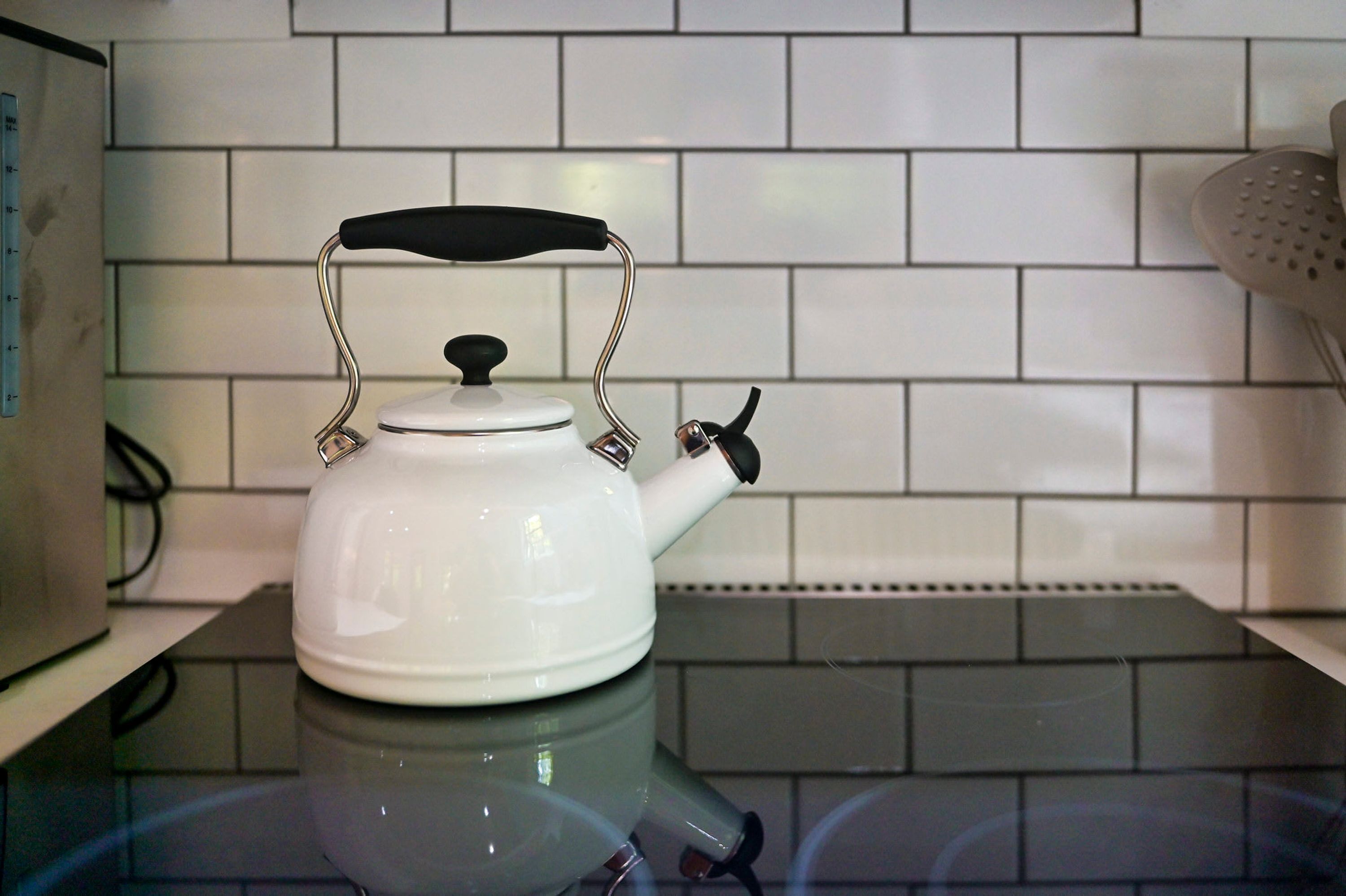 A white kettle on a kitchen counter with a tiled backsplash.