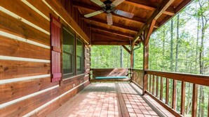 A wooden cabin with a porch, a ceiling fan, and a view of a forest. - Pigeon Forge Cabin Game Room Dog Friendly Hot Tub (Pigeon Forge)