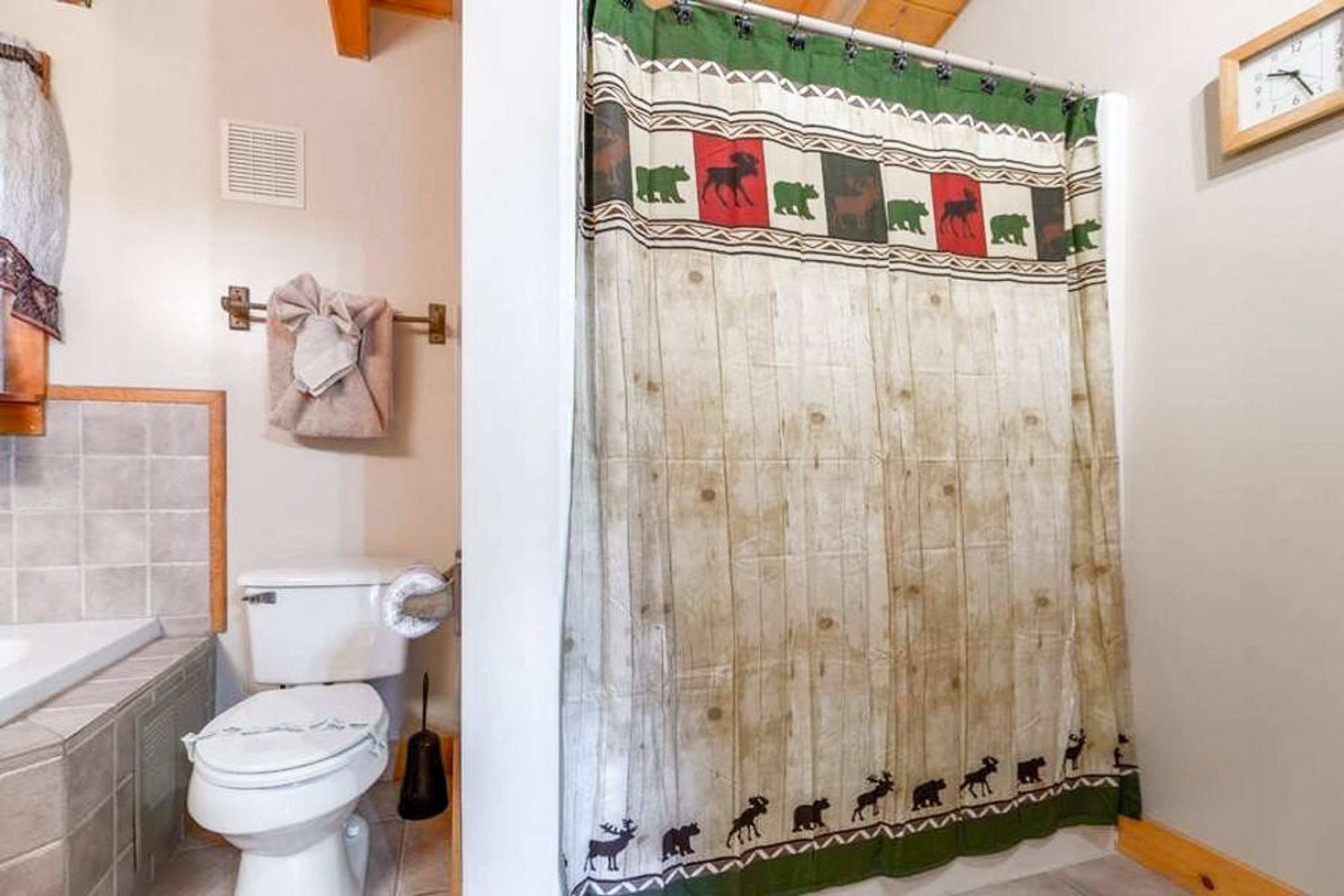 A bathroom with a toilet, a towel rack, and a shower curtain with animal patterns.