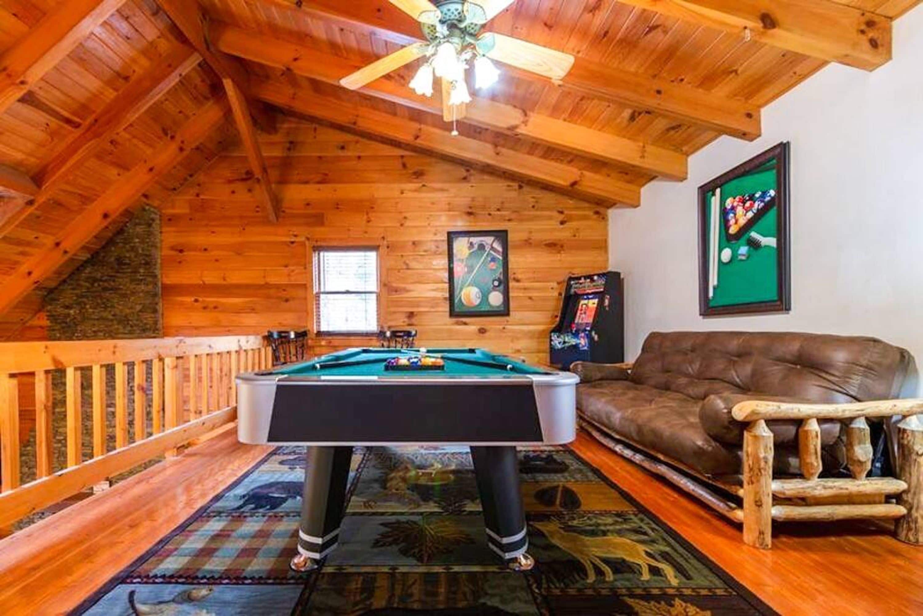 A cozy room with a pool table, a brown leather couch, and a ceiling fan.