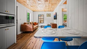 A modern kitchen with white cabinets, a wooden ceiling, and a dining area with a white table set for four. - 2bdrm Cabin 2 Gburg Pet Friendly Fire Pit Game (Gatlinburg)