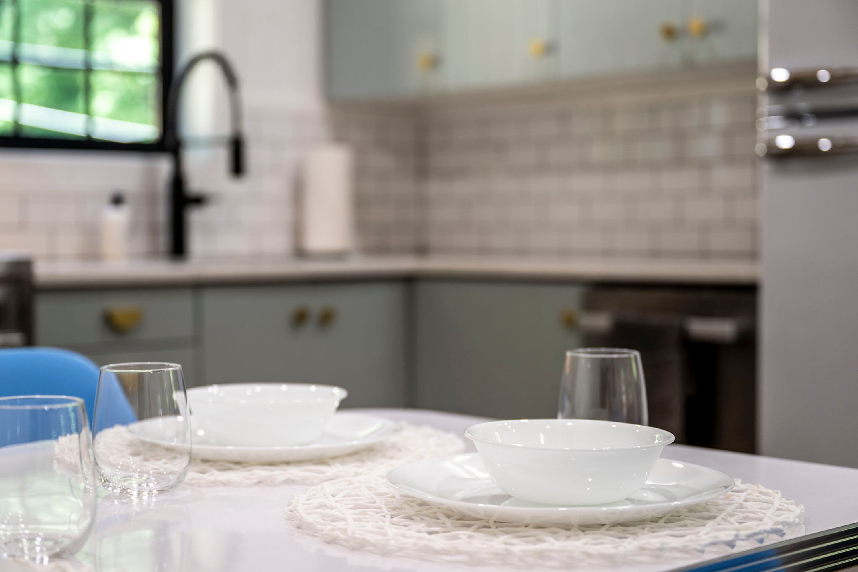 Una mesa de comedor con platos, tazones y vasos blancos, sobre un mantel blanco con un copo de encaje.
