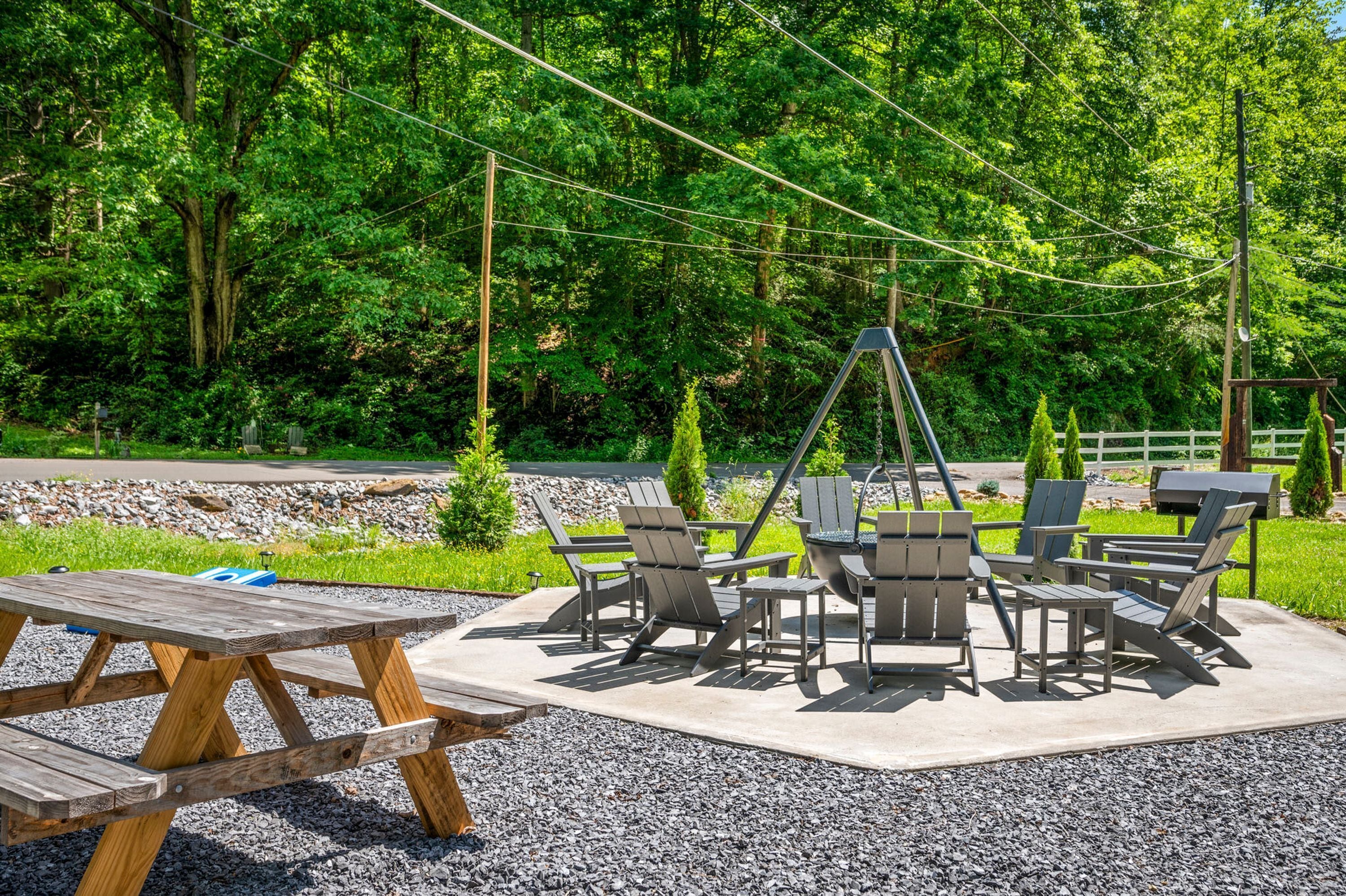 A picnic area with a concrete table and chairs, surrounded by gravel and greenery.