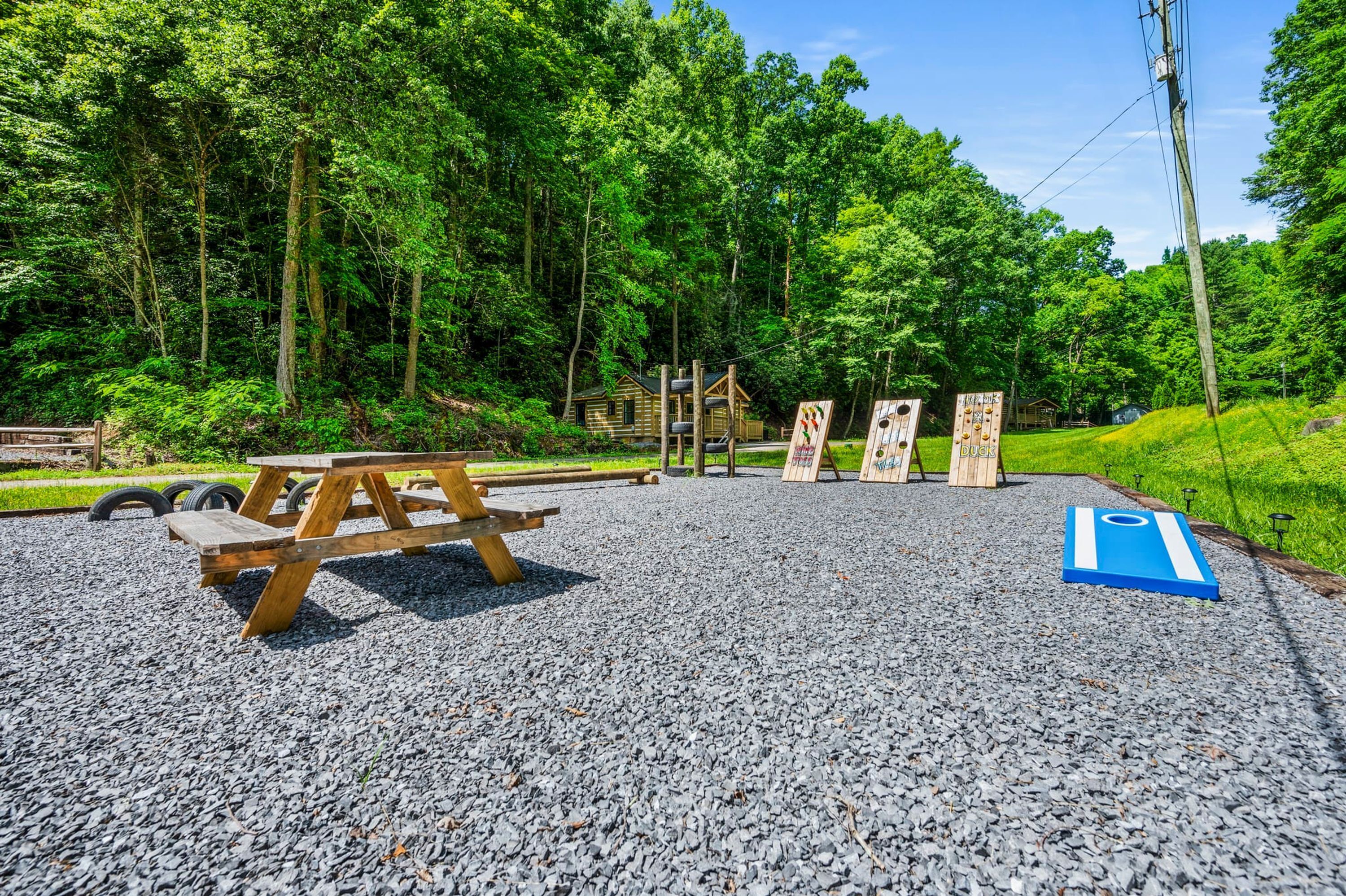 A picnic area with a wooden table and benches, surrounded by a forested area.
