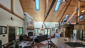 Eine geräumige Küche mit Kamin aus Stein, Holzbalkendecke und einer großen Kochinsel.