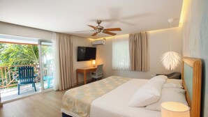 Un dormitorio con cama, escritorio, silla, ventilador de techo y balcón con sillas.