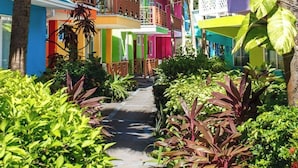 Un sendero bordeado por edificios coloridos y exuberante vegetación tropical.