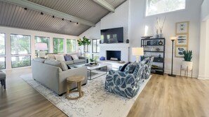 A spacious living room with a fireplace, large windows, and a modern design. - 6961 Fairway One at The Sea Pines Resort (Hilton Head Island)