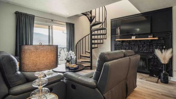 A modern living room with a sofa, a coffee table, a TV, and a fireplace.