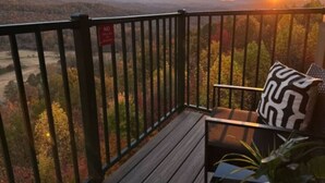 A balcony with a view of mountains and a sunset.