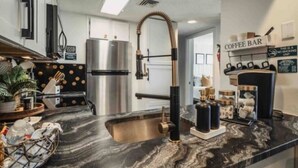 A modern kitchen with a stainless steel refrigerator, a coffee bar, and a marble countertop.