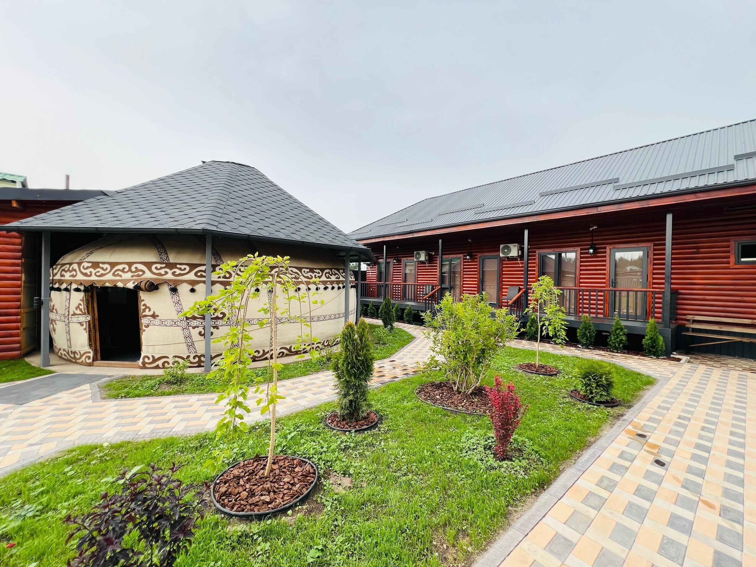 Un edificio in stile baita di legno tradizionale con un cortile in pietra e un piccolo giardino.