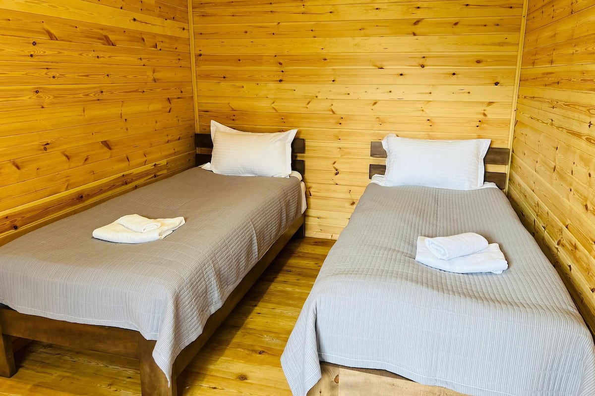 A cabin with two wooden bunk beds, each with a pillow and a folded towel.