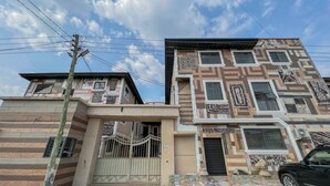 A two-story building with a patterned facade, a gated entrance, and a parked car. - Cozy minimal suite 1-bedroom apartment with AC, WiFi in serene Accra (Accra)