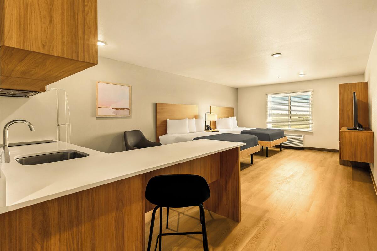 A modern kitchen with a wooden countertop, a sink, and a bar stool.