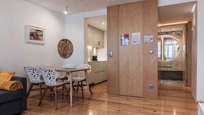 A modern interior with a dining area, a kitchen, and a bathroom with a marble floor.