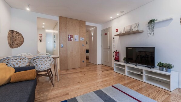 Una sala de estar moderna con un sofá, televisor y suelo de madera.