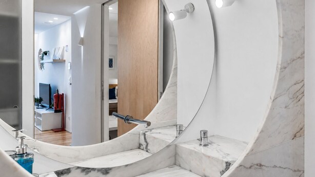 A bathroom with a large mirror, a marble countertop, and a modern faucet.