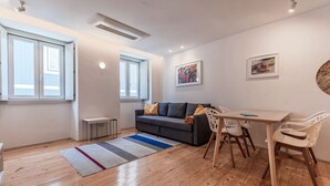 A modern living room with a sofa, dining table, chairs, and artwork on the walls.