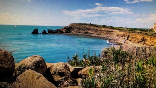 A coastal landscape with clear blue waters, rocky formations, and vegetation. - Cap d'agde - Appart 2 pers. Quiet ground floor with swimming pool - close to beach and shops (Agde)
