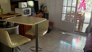 A kitchen with a dining area, a microwave, a toaster, and a painting on the wall. - Cap d'agde - Appart 2 pers. Quiet ground floor with swimming pool - close to beach and shops (Agde)