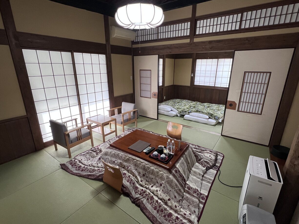 A traditional Japanese room with tatami flooring, a low table with tea set, and sliding doors.