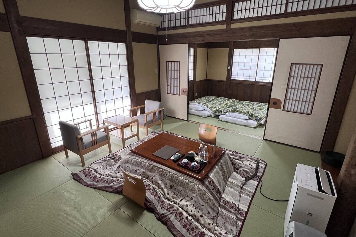 A traditional Japanese room with tatami flooring, a low table with tea set, and sliding doors.
