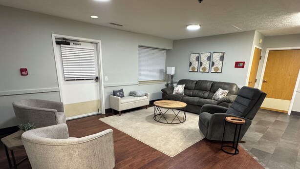 A living room with a grey sofa, a grey armchair, a wooden coffee table, and a beige rug.
