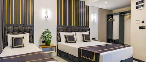 A hotel room with two beds, a potted plant, a mirror, and a hanging light fixture.