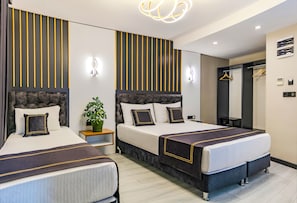 Habitación de hotel con dos camas, una planta en maceta, un espejo y una lámpara colgante.