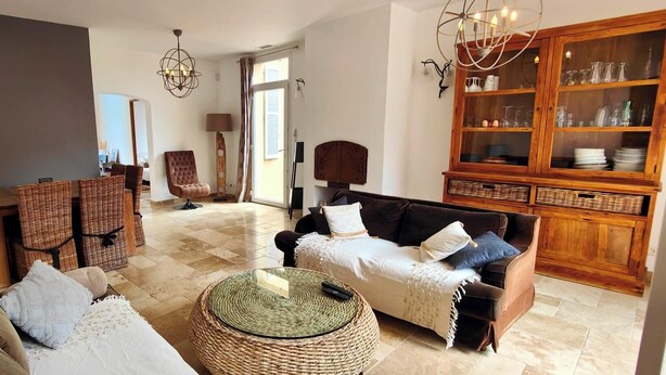 Un salon comprenant un canapé, des fauteuils, une table basse et un meuble contenant de la verrerie.