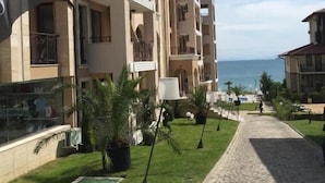 A multi-story hotel with balconies, a paved walkway, and a view of the sea. - Porto Paradiso Apartments (Sveti Vlas)