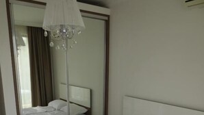 A hotel room with a large bed, a mirror, and a chandelier. - Porto Paradiso Apartments (Sveti Vlas)