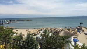 A beach with umbrellas and beach chairs, a pier, and a clear sky. - Porto Paradiso Apartments (Sveti Vlas)