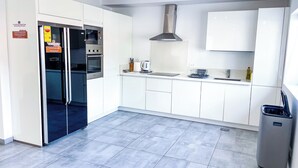 A modern kitchen with white cabinets, a built-in oven, microwave, and a stainless steel range hood.