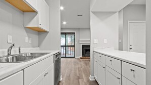 Une cuisine moderne avec des meubles blancs, un évier en acier inoxydable et un plancher en bois.