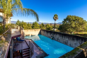 Ein Schwimmbad mit Holzterrasse und Bergblick.