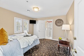 Ein Hotelzimmer mit einem Bett, einem kleinen Tisch, einem Fernseher, einer Tür und einem gemusterten Teppich.