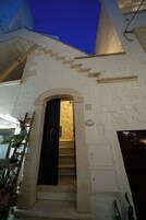 A white building with a black door and a staircase leading to the entrance.