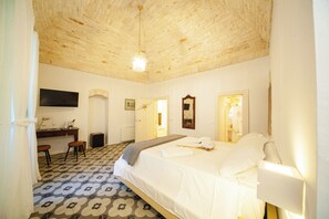 A bedroom with a bed, a desk, and chairs. There is a mirror on the wall and a light fixture on the ceiling. - Bella Itria (Locorotondo)